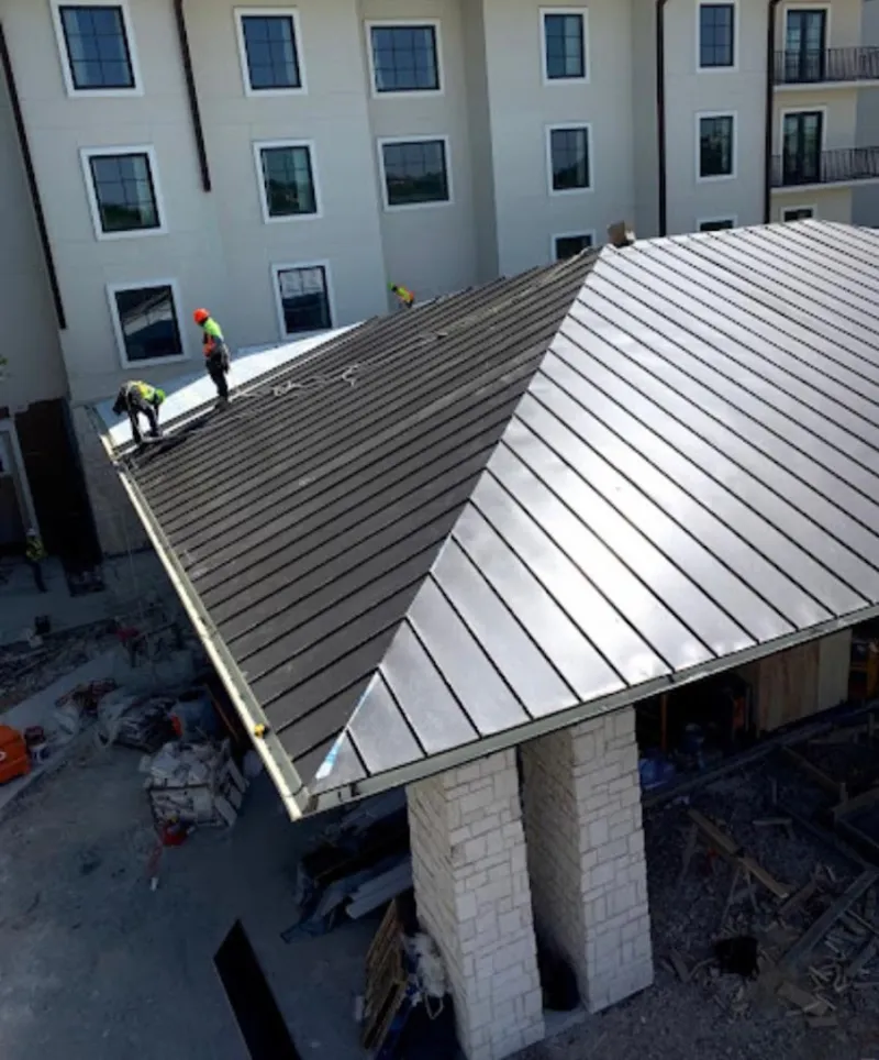Crew installing standing seam metal roof panels on a commercial project in New Bern